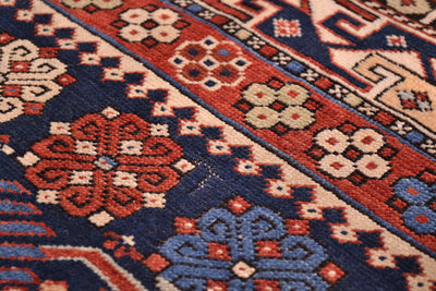 Rug close-up of floral medallions and corner designs in navy, red, and cream tones.