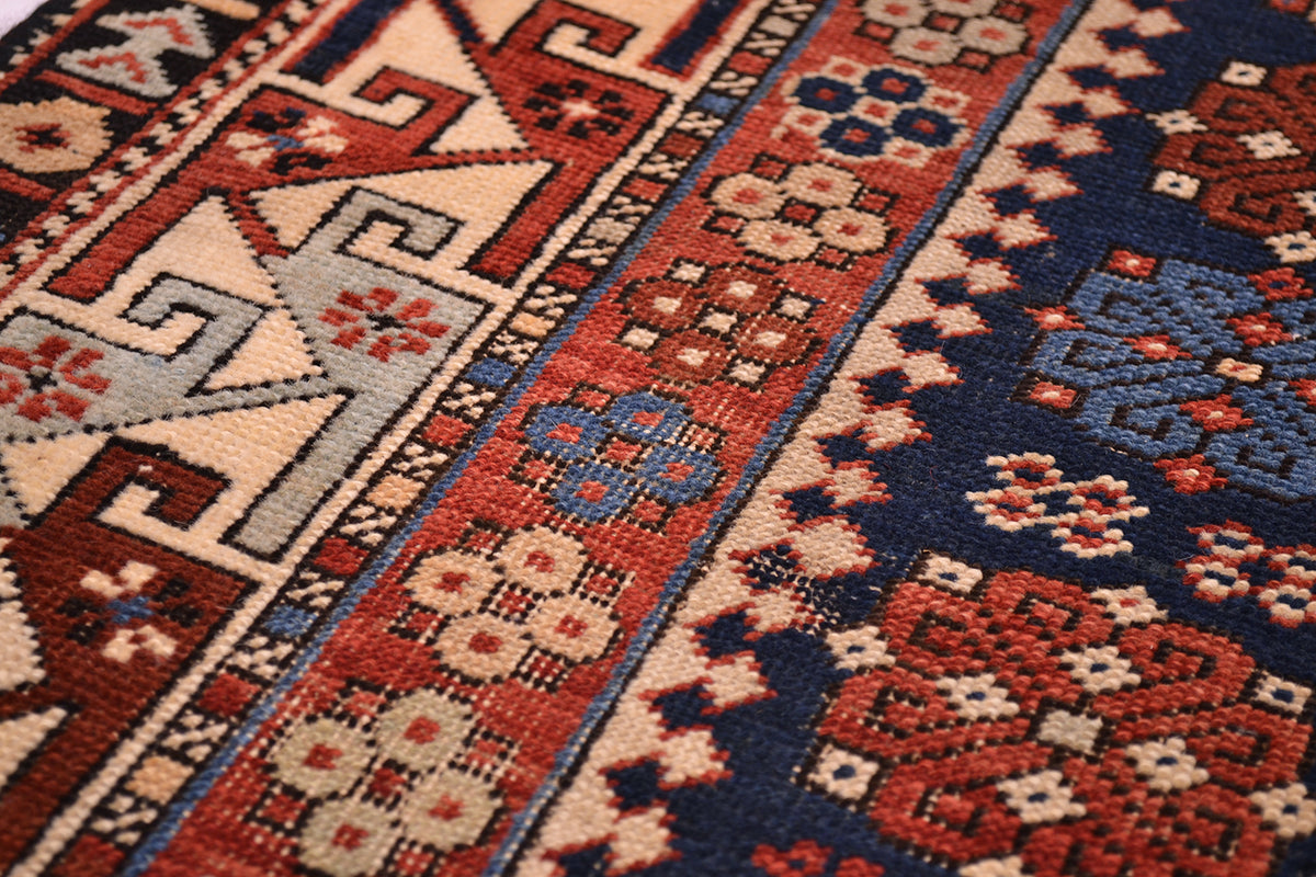 Rug close-up showing cream and rust geometric blocks on navy with small floral accents.