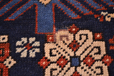 Rug texture close-up with navy field and cream medallion shapes outlined in red-orange.