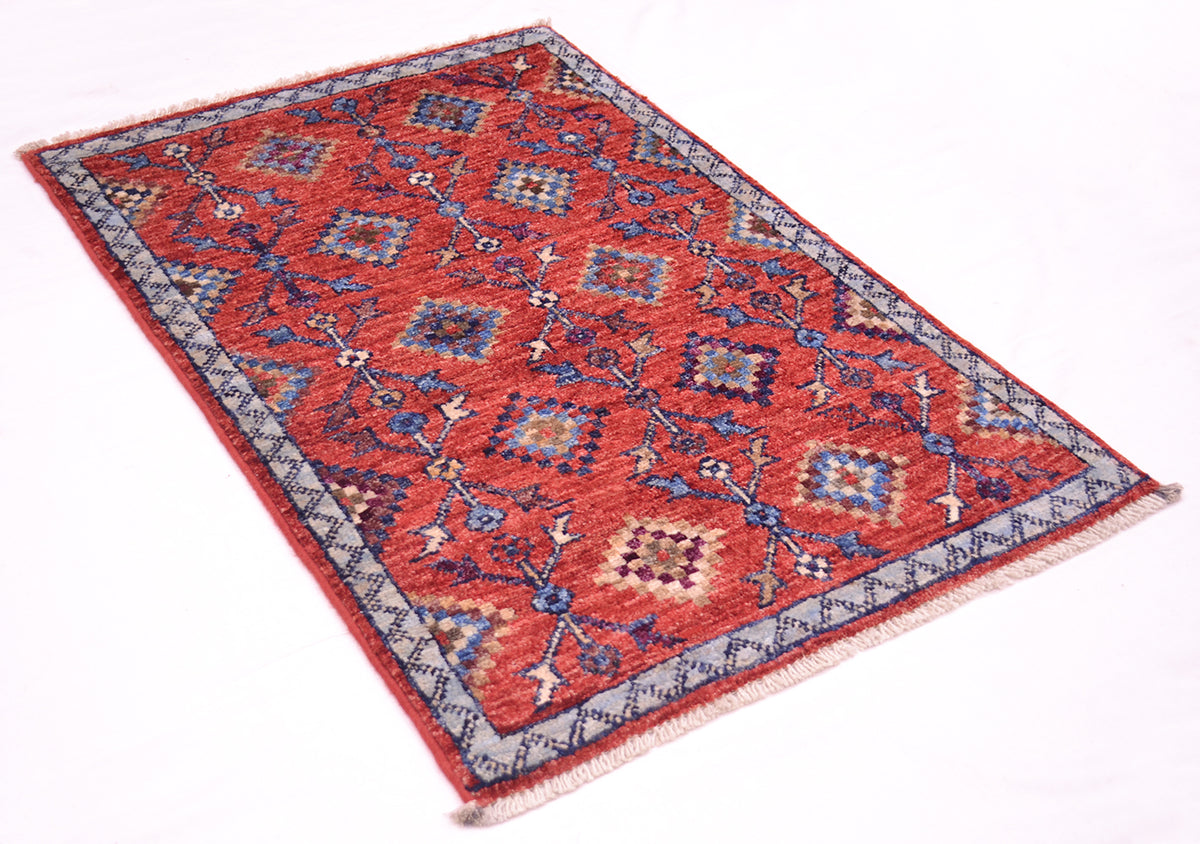 A traditional rectangular Afghan Chobi tribal design mat with a red field, blue and beige geometric motifs, and a patterned border, shown on a plain white background.