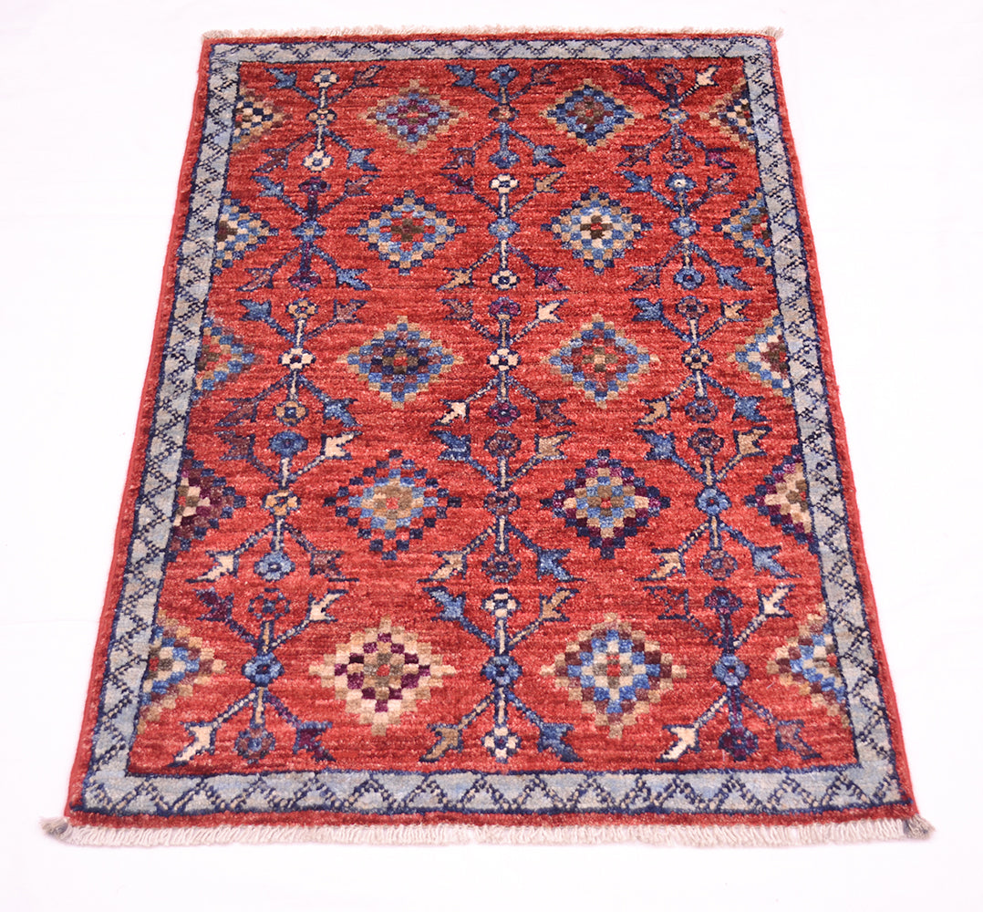 A rectangular hand-woven Afghan Chobi tribal design doormat sized rug with a traditional geometric pattern in red, blue, beige, and grey, featuring a fringed edge on a white background.