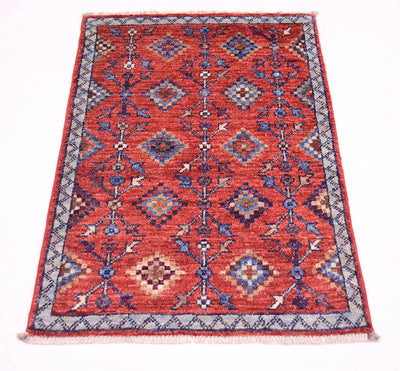 A rectangular hand-woven Afghan Chobi tribal design doormat sized rug with a traditional geometric pattern in red, blue, beige, and grey, featuring a fringed edge on a white background.