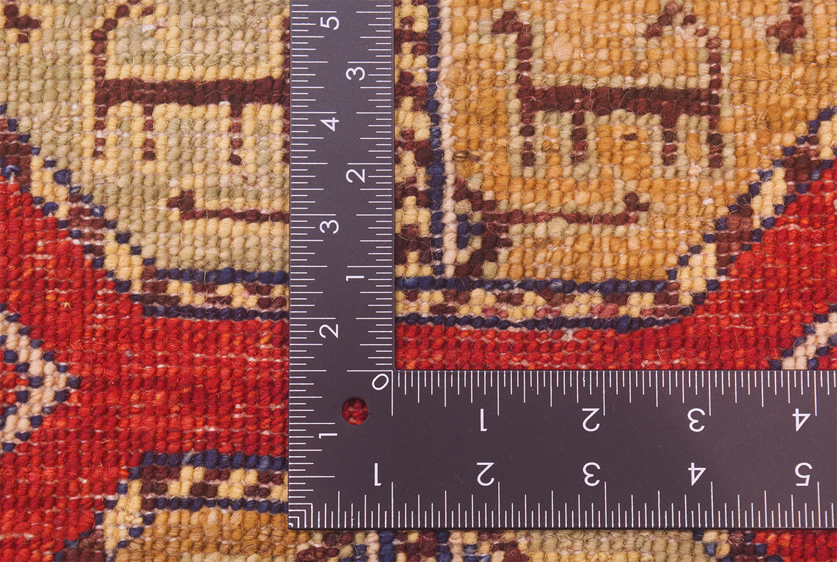 Close-up of the hand-knotted weave of a patterned Afghan Fil Pai small rug with a dark metal L-shaped ruler placed over it for scale of the knotting, showing a red, beige, and brown woven design.