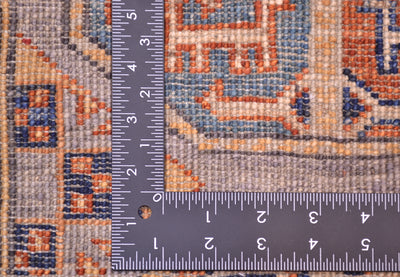 Close-up of the hand-knotted weave of a Afghan Fil Pai patterned small rug with a metal L-shaped ruler showing measurements in inches to indicate scale of the knotting.