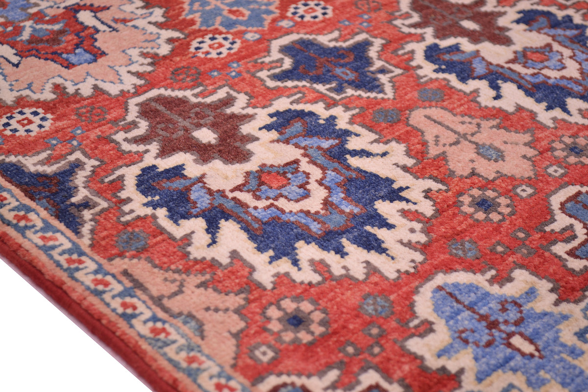 A close-up of a traditional patterned Afghan Chobi Mat with a red, blue, and beige floral design, showing the texture and corner detail.