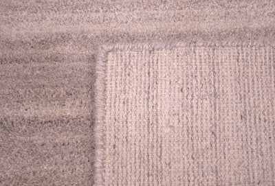 Close-up of a textured hand-knotted runner corner showing a woven pattern in a warm grey, taupe-beige colour.
