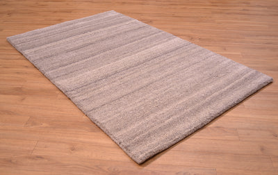 A Grey Indian runner with a textured, taupe and light brown striped pattern, shown laid out on a light brown wooden floor.