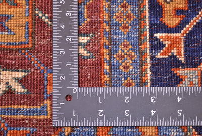 Close-up of the weave of a handmade Afghan blue Ersari carpet with a metal L-square ruler showing measurements in inches to help visualise the scale of the hand-knotting.