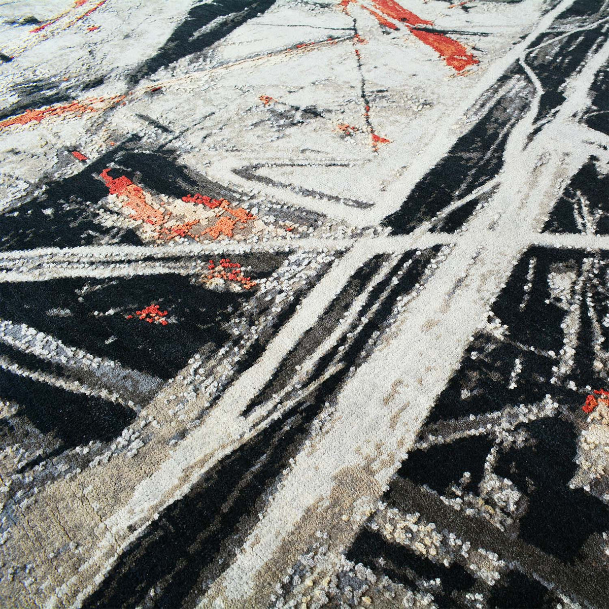 Close-up of Expression abstract handmade rug wool and silk fibres: grey, black, and red textured lines.