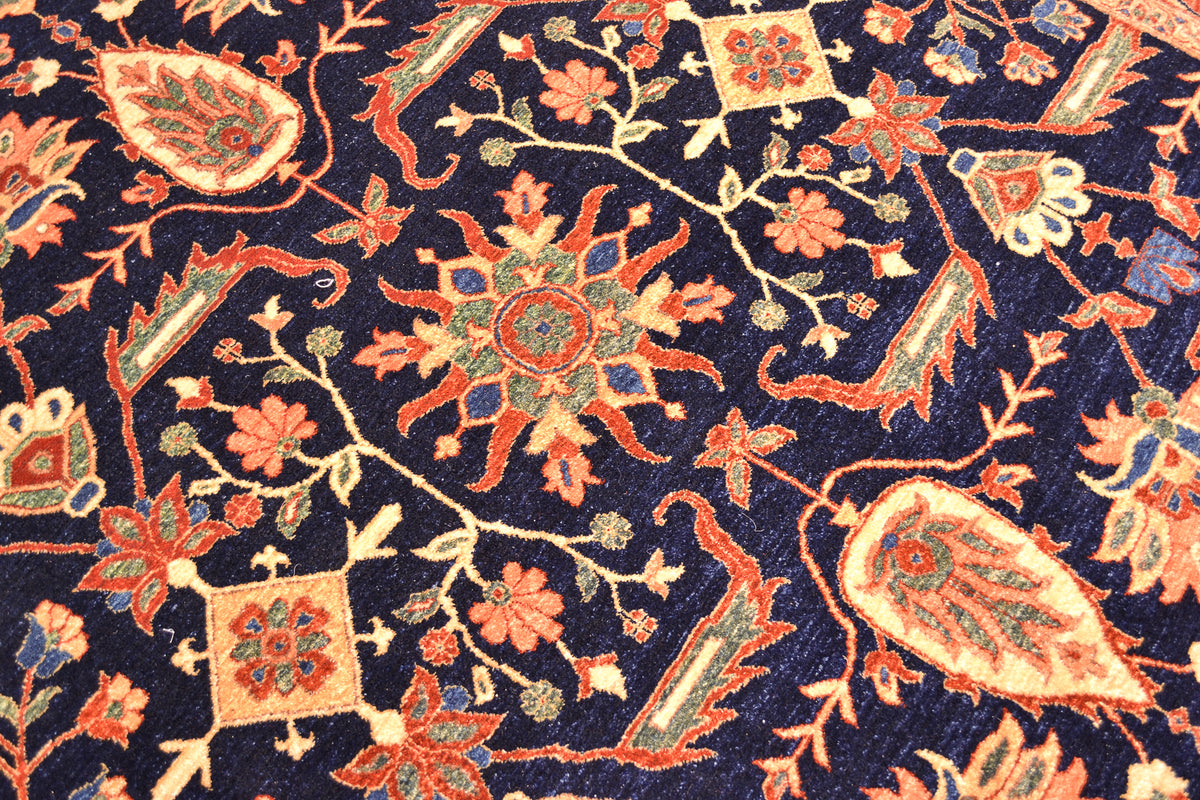 Close up detail of main field of Fine Ferahan carpet with pure wool pile. Deep rich midnight blue ground background of main field with interconnecting floral motifs of traditional floral design in contrasting colours.
