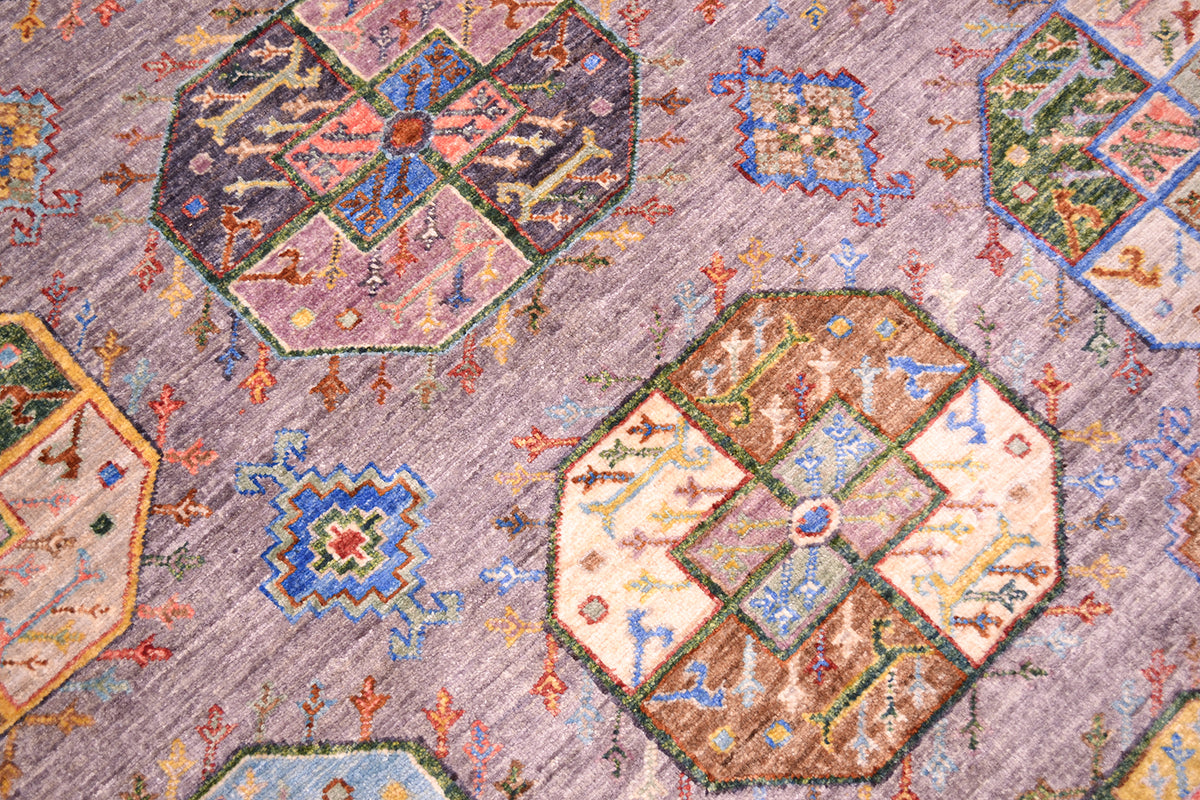 A close-up of an elephants foot patterned Afghan area rug with geometric octagonal medallions and small floral motifs on a grey background.
