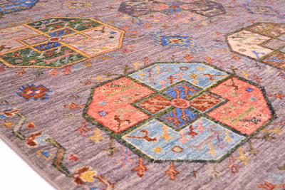 A close-up of a traditional Afghan Fil Pai patterned rug with a muted grey base and large geometric medallions in coral, light blue, green, and brown.