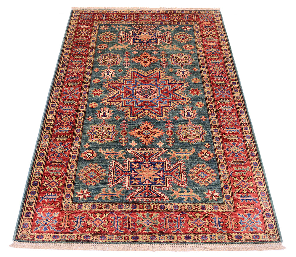 A rectangular vintage-style area rug with a complex geometric and floral pattern, featuring a teal blue center field, red borders, and cream accents, shown flat against a white background.