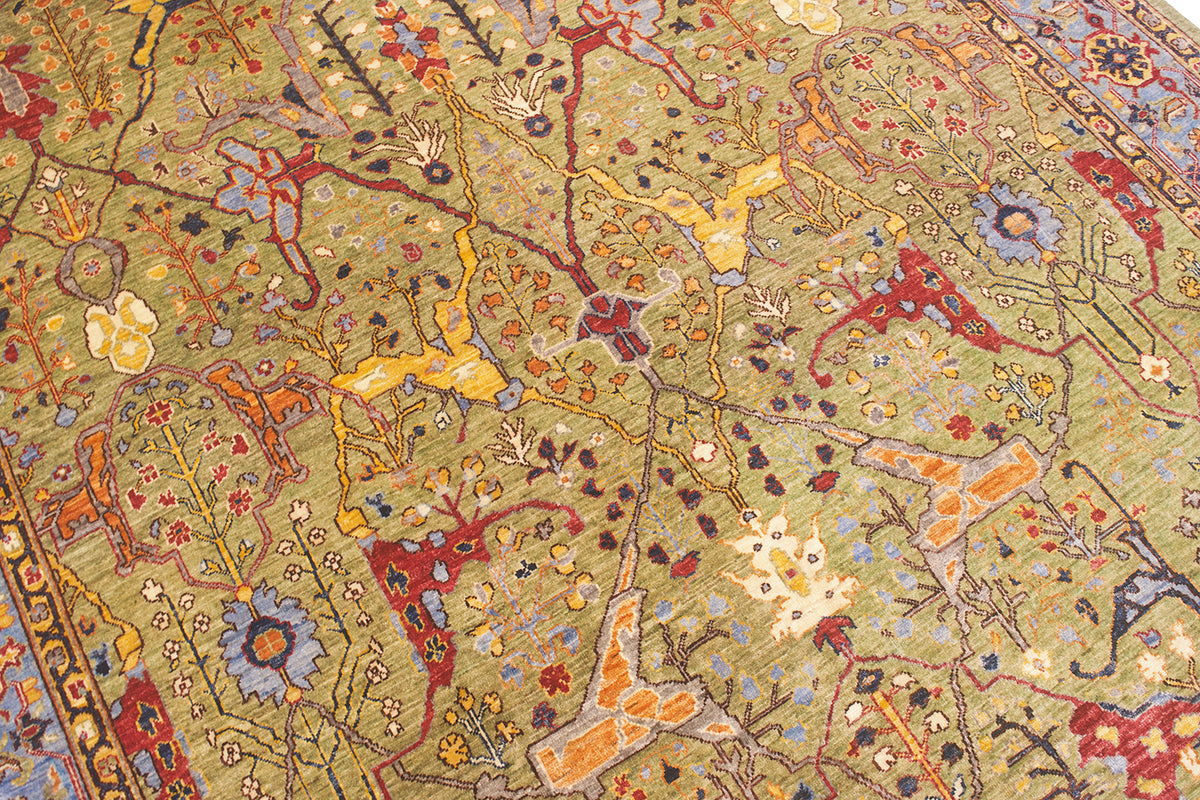 Close up detail of soft lush green ground of a traditional antique garous design with secondary colours of red, light and dark blue, red, cream, amber orange and  yellow gold. 