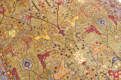 Close up detail of soft lush green ground of a traditional antique garous design with secondary colours of red, light and dark blue, red, cream, amber orange and  yellow gold. 
