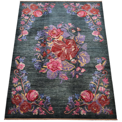 A rectangular Handmade Afghan Gul Ferang carpet with a dark green background and a central floral motif in red, pink, purple, and gold, surrounded by matching floral corner designs.