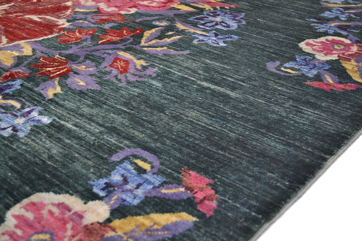 A close-up of a textured Afghan floral area rug with a dark green base and a vibrant floral pattern in pink, purple, red, and yellow.