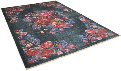 A rectangular area Afghan floral rug with a dark green background and an ornate floral pattern in red, pink, purple, and blue, shown from an elevated angle on a white background.