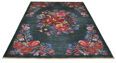 A rectangular Afghan floral area rug with a dark teal-green background and an ornate floral pattern in red, pink, purple, blue, and gold, shown from an overhead angle on a white background.