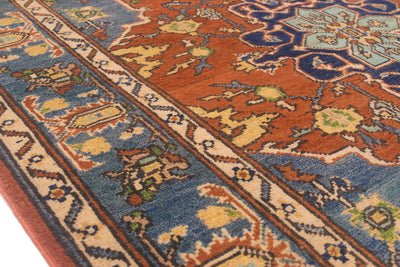 A close-up of a traditional patterned Heriz area rug showing a rust-orange field, blue borders, and cream details.