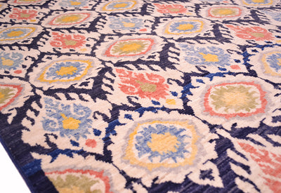 Angled close up view of handmade carpet with mixture of colours and flamelike ikat design medallions in an all over design.