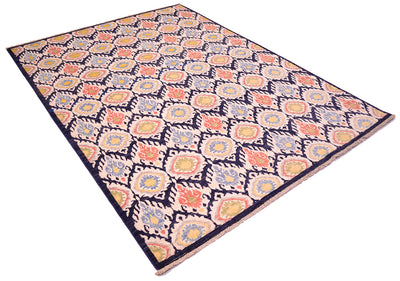 Angled view of handmade carpet from Afghanistan with all over design of ikat tetile patter with dark blue ground, cream, coral, green, gold yelloe and light blue.  Cotton warp short fringe.