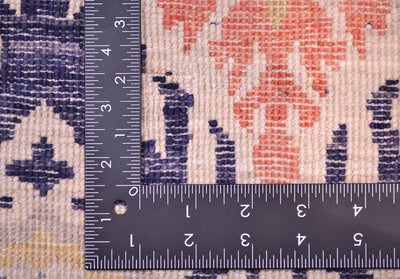 Back of carpet showing handknotting of pure wool pile with light terracotta coral, dark blue, cream as well as grey and yellow.