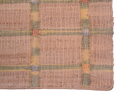 A close-up of a woven rug or textile showing a plaid pattern in muted earthy tones, including dusty pink, beige, olive green, mustard yellow, and soft orange.