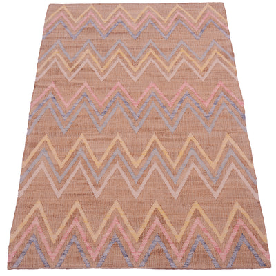 A rectangular woven area rug with a chevron pattern in dusty pink, beige, light blue, and cream on a warm tan background.