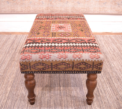End view of kilim bench upholstered with a vintage kilim with softened colours of light olive green, soft grey blues, rose terracottas and soft brown with white highlights. Placed on a neutral afghan handmade carpet.