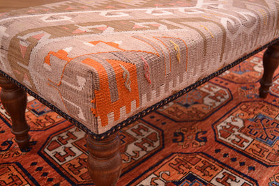Close up design of kilim bench with vintage kilim with beaded edging and soft pastels colours with hints of oragen and coral pinks as well as beige and  light olive greens.