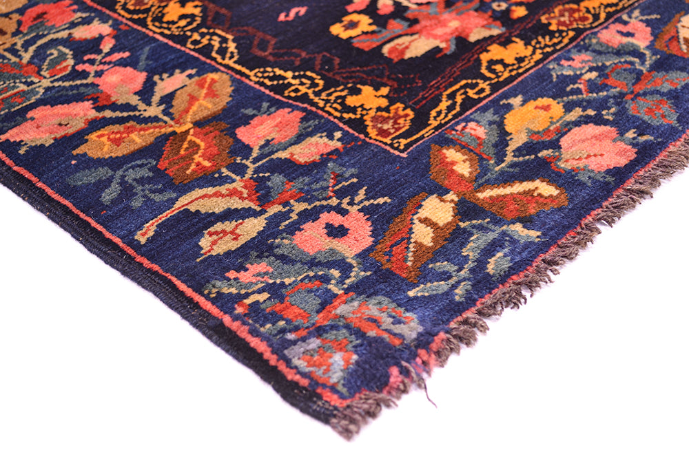 Corner detail of antique rug with wooled warp fringe with wear. Deep blue border background with intense blue, indigo black main field ground. 