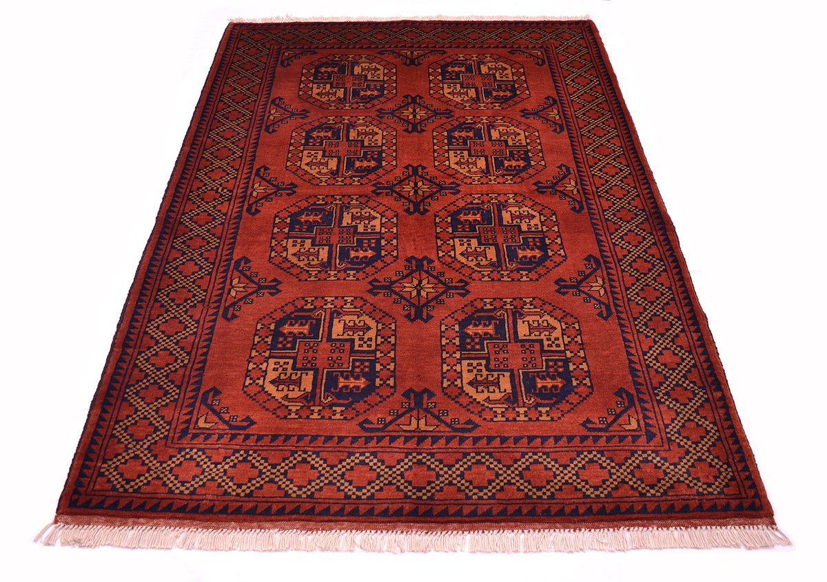 A traditional oriental Afghan rug with a deep rusty-red field, featuring geometric fil pai guls and a patterned border in dark blue-black, and soft orange, finished with cream fringe.