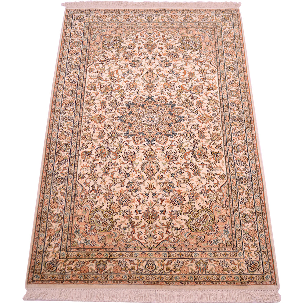 A traditional silk area rug with an intricate floral and medallion pattern, featuring a cream base with dusty pink, blue, and green accents
