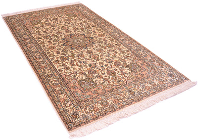 A fine silk  rug with a traditional floral pattern, featuring a central medallion, decorative borders, and cream-colored fringe on the ends, shown against a plain white background.
