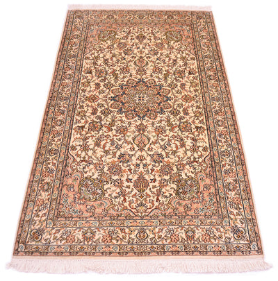 A rectangular silk area rug with a traditional floral and medallion pattern, featuring a beige and peach base with brown, blue, and rust accents, finished with white fringe on the ends.