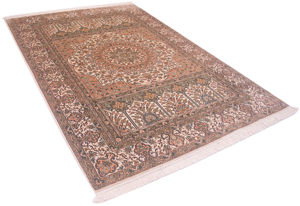 A silk Kashmir area rug with a traditional floral and geometric pattern, featuring a warm center, beige and brown borders, and fringes on the ends, shown from an elevated perspective against a white background.
