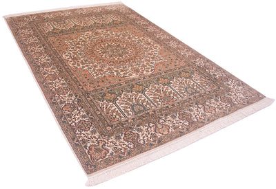 A silk Kashmir area rug with a traditional floral and geometric pattern, featuring a warm center, beige and brown borders, and fringes on the ends, shown from an elevated perspective against a white background.