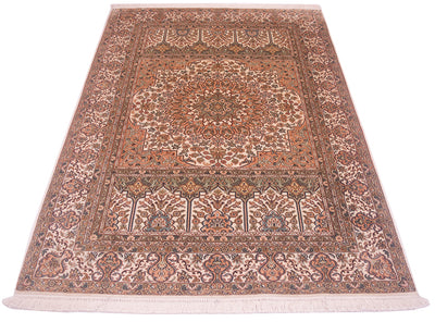 A silk Kashmir rug with an intricate floral pattern in shades of terracotta, beige, brown, and muted blue, featuring a central medallion and fringes