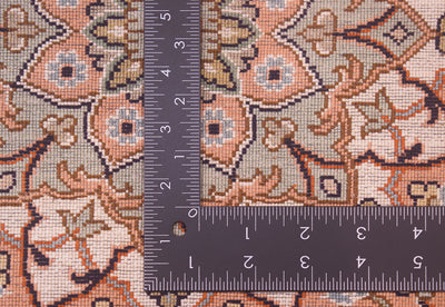 Close-up of the back of a silk Kashmir rug with a  L-shaped ruler placed over it to show scale, featuring a beige, peach, and navy ornamental floral design.