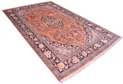 A traditional Silk Kashmir rug with a dusty pink center, navy blue borders, and beige floral motifs, shown from an elevated angle on a white background.