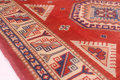 Close-up of red Kazak rug border with geometric zigzag and diamond motifs