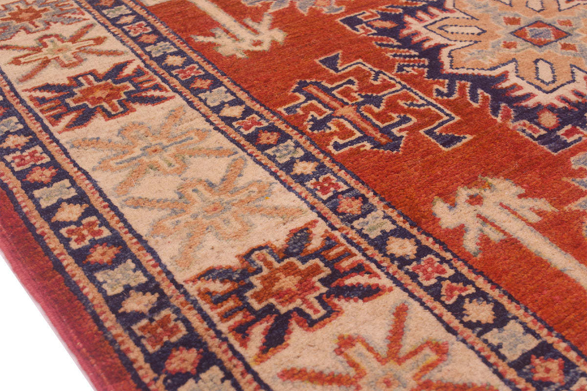 Kazak rug border close-up with blue lines, cream panels, and rust-red geometric motifs