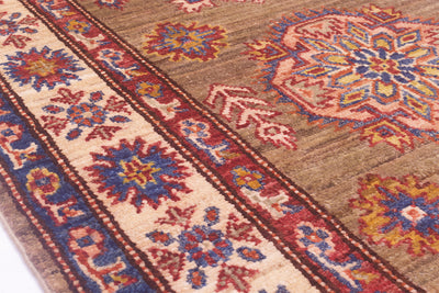 A close-up of a traditional patterned Afghan runner rug with a brown field, cream border, and red, blue, and yellow floral medallions.