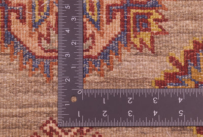 Close-up of the hand-knotted back of a patterned extra long handmade Afghan Kazak runner with a dark metal L-square ruler placed over it to show scale, highlighting the detailed woven textile in beige, blue, red, and yellow tones.