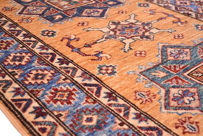 A close-up of a traditional patterned fine Afghan Kazak small rug with a warm amber yellow field, blue and red geometric borders, and central medallion motifs.