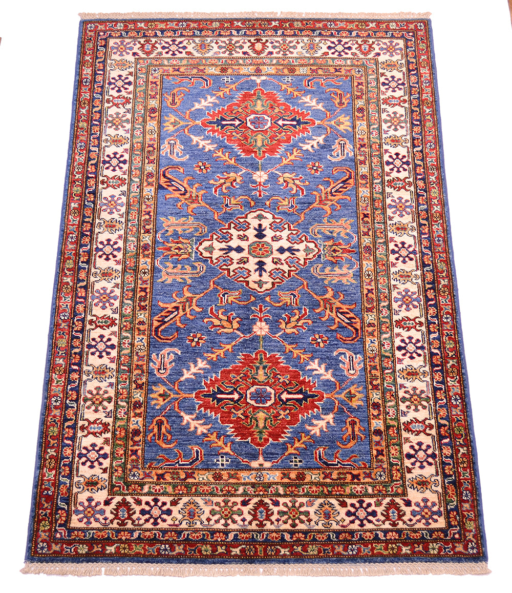 A traditional handmade Fine Kazak wool Rug with a blue central field, red and beige medallions, and a detailed multicolor border, shown flat against a white background.
