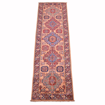 A traditional handmade fine Kazak runner rug with a peach-pink field, featuring red and blue medallions and floral motifs, bordered by red and navy blue patterns, shown flat against a white background.