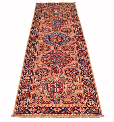 A long rectangular Afghan Kazak runner rug with intricate geometric and floral motifs in peach, navy, red, beige, and green, shown flat against a white background.
