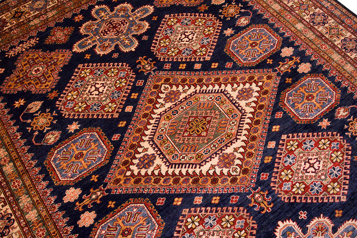 Close-up of navy kazak rug shows red, orange, and cream geometric motifs